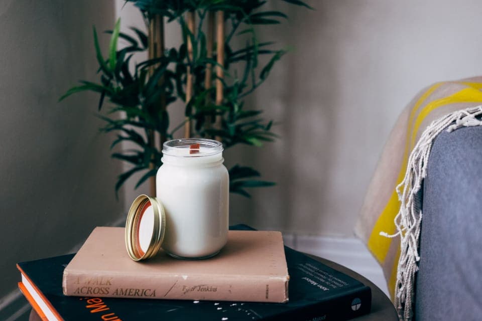 Vela en frasco de vidrio sobre libros
